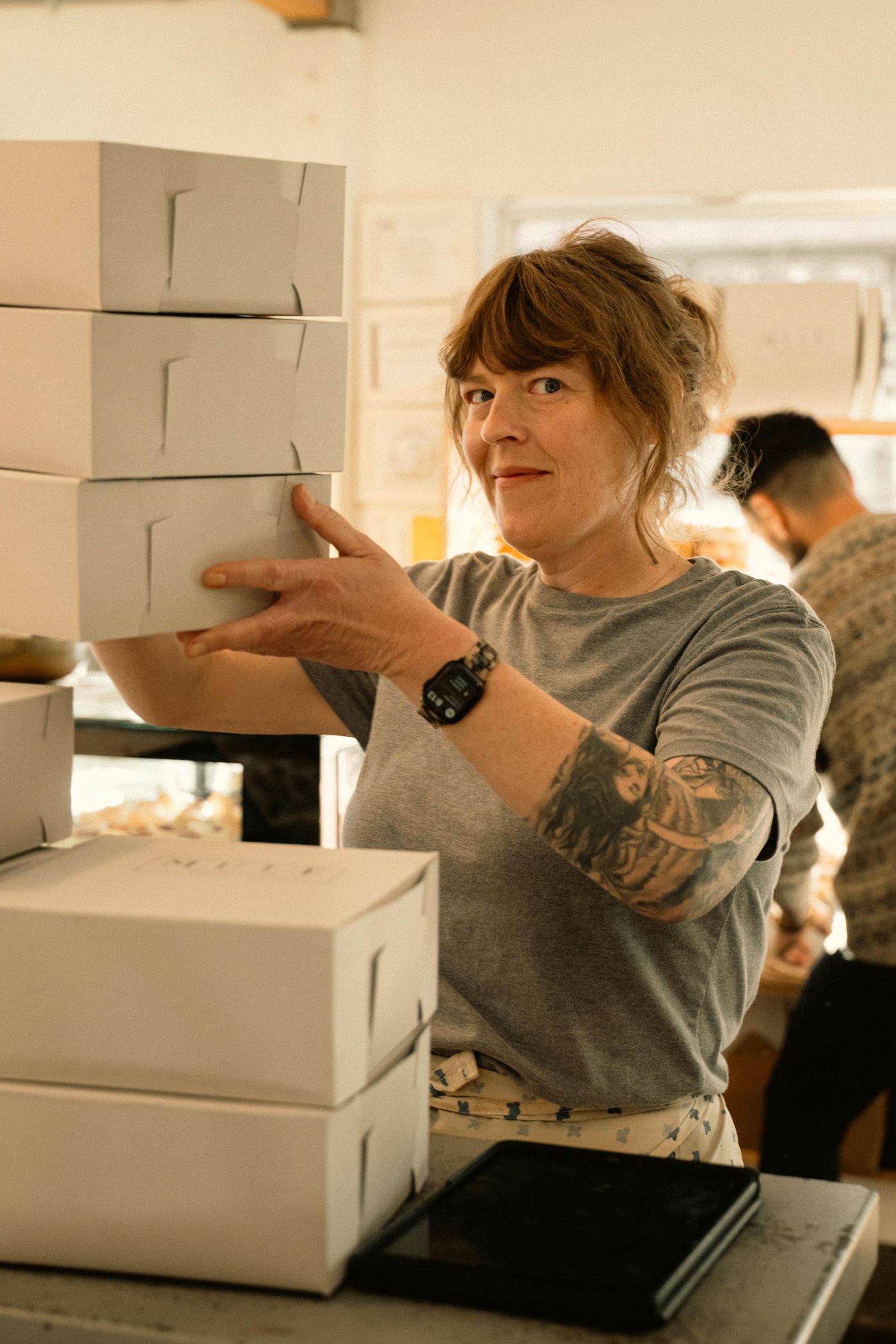 A happy bakery owner stacking boxes in her shop